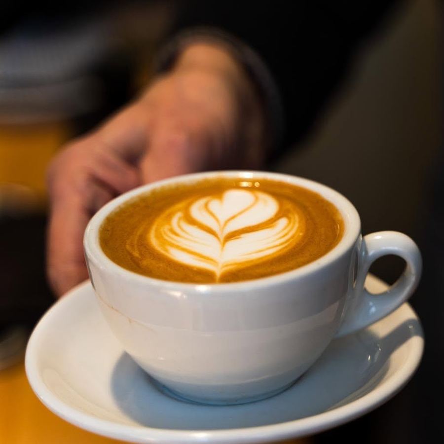 A cappuccino with latte art, served on a white saucer